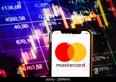 KONSKIE, POLEN - 07. August 2022: Smartphone mit Logo von Mastercard Inc auf dem Hintergrund des Börsendiagramms Stockfoto