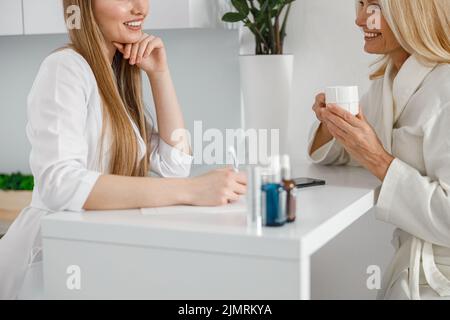 Seitenansicht einer lächelnden Kosmetologin spricht mit ihrem Klienten im Kosmetikkabinett Stockfoto