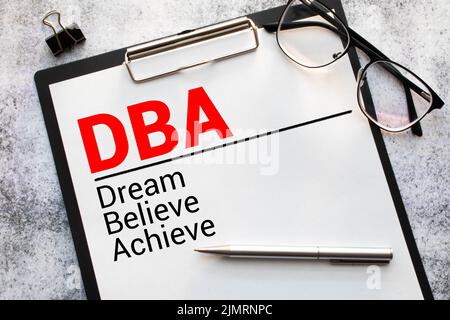 Hand eines Geschäftsmanns, der das Puzzle mit dem letzten fehlenden Stück vervollständigt.Konzeptbild der Geschäftsbezeichnung DBA As Dream Believe Achieve Stockfoto