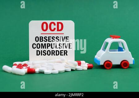 Medizinisches Konzept. Auf einer grünen Fläche, einem Krankenwagen, Pillen und einem weißen Schild mit der Aufschrift - Zwangsstörung Stockfoto