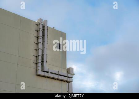 Metallene Lüftungsrohre vor einem Gebäude in San Francisco, Kalifornien. Niedriger Blick auf ein modernes Gebäude mit einer dunkelbeigen Außenwand Stockfoto