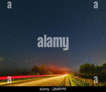 Komet Neowise C2020 F3, wie er im Sommerhimmel über einer Wiese in der Nähe der Landstraße, Region Lviv, Ukraine fliegt. Stockfoto