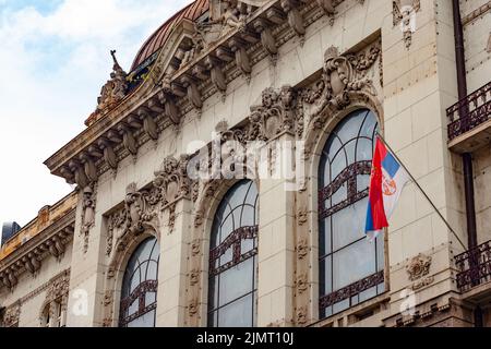 Serbische Flagge fliegt, Downtown Business Building mit Verzierungen ist im Barockstil aus dem 19.. Jahrhundert. Belgrad, Serbien hat Stil und Schönheit. Stockfoto