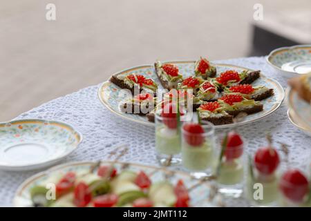 Köstliche Snacks auf dem Hochzeitstisch im luxuriösen Restaurant im Freien. Sandwiches mit rotem Kaviar und Salatcocktails. Stockfoto