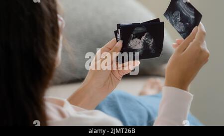 Rückansicht schwanger unkenntlich fruchtbar Frau Mädchen Zukunft Mutter Frau sitzt auf dem Sofa zu Hause und beobachtet Ultraschall-Bilder von Keimkind genießen Stockfoto