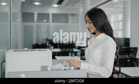 Arabisch hispanische Geschäftsfrau Mädchen Arbeiter Sekretärin macht Kopien auf Kopierer verwenden Büroausstattung Druckmaschine replizieren Papiere senden Fax drucken Stockfoto