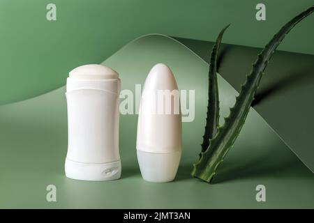 Festes Antitranspirant, Deodorant und zwei frische Aloe-Blätter auf wellig-grünem Hintergrund. Natürliche Kräuterkosmetik für die Hautpflege. Toilettenartikel. Stockfoto