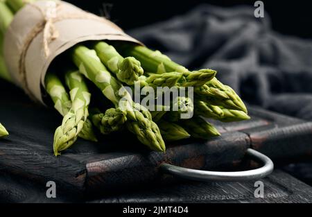 Ein paar frische rohe Spargel auf einem schwarzen Holzbrett, ein gesundes Produkt Stockfoto