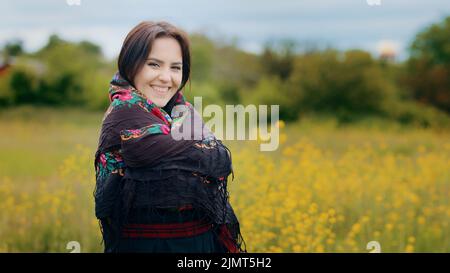 Junge stilvolle Frau attraktives Mädchen verbringen Zeit allein im Freien trägt ukrainische traditionelle Kleidung schwarze Kleidung halten flatternd gemustert bunt Stockfoto