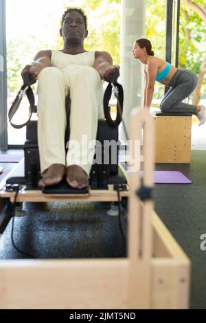 Konzentrierter afroamerikanischer Mann, der Pilates-Dehnübungen übt Stockfoto