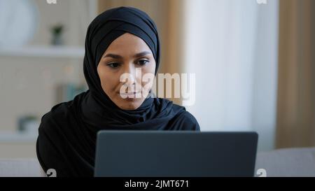 Fokussierte ethnische weibliche muslimische arabische junge Frau Mädchen islamischen Studenten Geschäftsfrau Freiberufler sitzt zu Hause Arbeit auf Computer Online-Chat-Suche Stockfoto