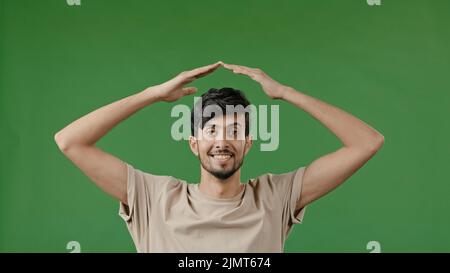 Hispanic junger Mann araber heben die Hände über den Kopf machen Haus Dachrahmen Geste mit Armen fühlen sich sicher Schutz im Traum von zu Hause Umzug Stockfoto