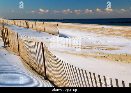 Schnee bedeckt den Sand am Strand von Avon am Meer, am Atlantischen Ozean an der Küste von Jersey, was eine leere Off-Season-Szene schafft Stockfoto
