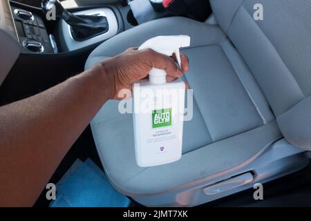 Erwachsene Mann sprühen Auto Innenraum Shampoo Reinigungsflüssigkeit auf Stoff Sitz Stockfoto