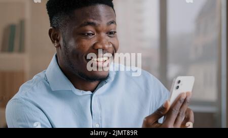 African american überrascht Mann Millennial 30s Geschäftsmann Mitarbeiter Besitzer halten mobile Gadget moderne Gerät Gespräch in Video-Chat auf Smartphone schockiert Stockfoto