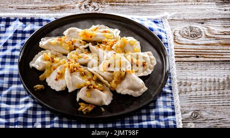 Komposition mit einem Teller klassischer Pierogien mit Zwiebeln Stockfoto