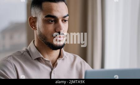 Nahaufnahme seriöse konzentrierte männliche Porträt arabischen Geschäftsmann Kerl hispanic Mann Freiberufler sitzen zu Hause Büro SMS-E-Mail auf Laptop verwenden persönlich Stockfoto
