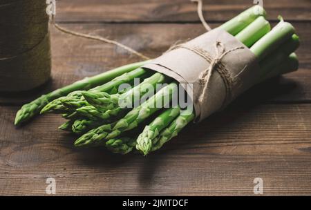 Bund frischer roher Spargel auf einem braunen Holzbrett, ein gesundes Produkt Stockfoto