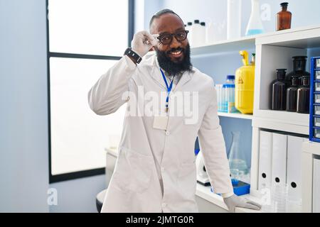 Junger afroamerikanischer Mann in Wissenschaftleruniform, der im Labor steht Stockfoto
