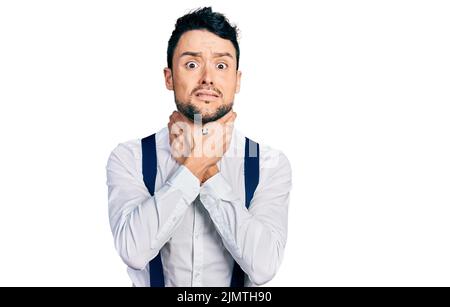 Hispanic Mann mit Bart trägt Hipster-Look mit Fliege und Hosenträger schreiend und ersticken, weil schmerzhafte Erwürgung. Gesundheitsproblem. Ersticken ein Stockfoto