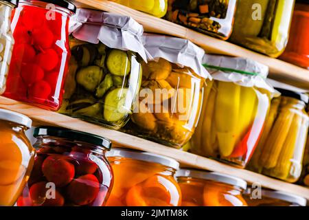 Gläser mit verschiedenen marinierten Gemüse und Früchten Stockfoto