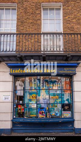 London, Großbritannien - 3. Juli 2022: Das farbenfrohe, blau umrahmte Schaufenster des London Beatles Store spiegelt das Bild von gegenüberliegenden Gebäuden in braunem Br Stockfoto