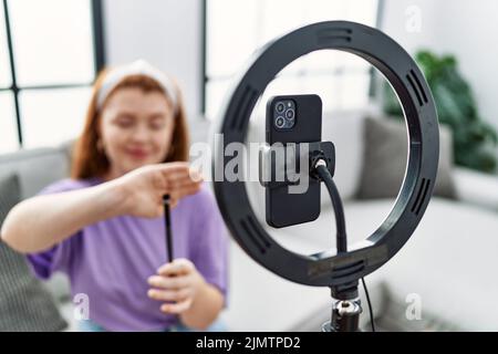 Junge Rotschopf Frau Make-up-Tutorial mit Smartphone zu Hause Stockfoto