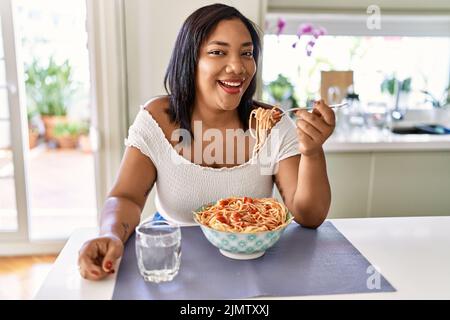 Hispanische Brünette Frau essen Spaghetti in der Küche Stockfoto