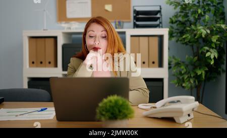 Junge Rotschopf Frau Geschäftsangestellte gestresst mit Laptop arbeiten im Büro Stockfoto