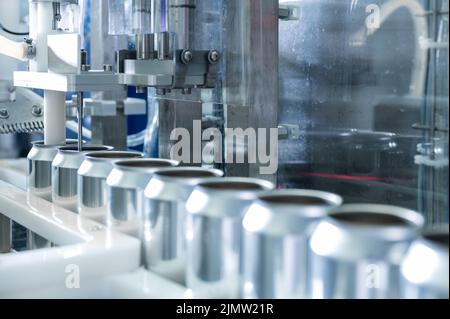 Leeren Sie neue Aluminiumdosen für den Getränkeprozess in der Produktionslinie auf der Förderbandmaschine bei der Getränkeherstellung. Lebensmittel und Getränke Stockfoto