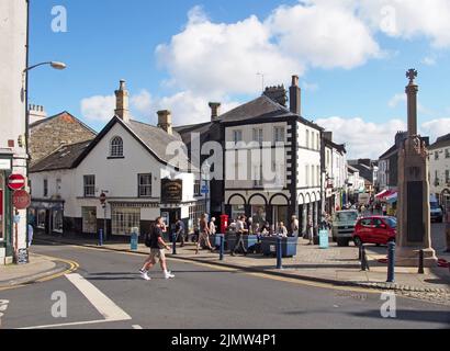 Blick auf das Stadtzentrum von ulverston cumbria mit Menschen, die an Geschäften und dem Wochenmarkt vorbeilaufen Stockfoto