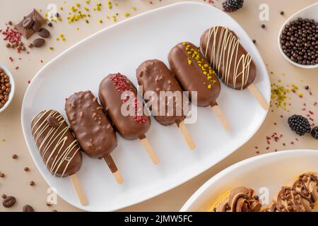 cupcake-Eis mit Schokoladencreme.Schokoladenkekse auf einem Stock in Form von Eis, Schokoladendekor, Schokoriegel und Kakaobohnen auf einem Stockfoto