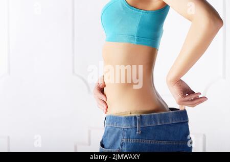 Kaukasische weibliche model in Blue Jeans Ihr flacher Bauch zeigt. Weightloss Konzept. Stockfoto