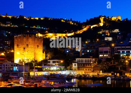 Nachtansicht der Stadtlandschaft von Alanya vom Hafenpier mit Blick auf den Roten Turm und die Burg Stockfoto