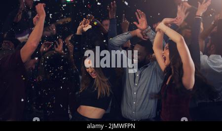 Es ist eine Silvesterfeier. Eine Gruppe junger Freunde tanzt zusammen in einem Nachtclub. Stockfoto
