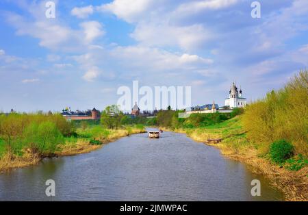 Susdal, Russland, 05.08.2022. Kamenka Tal unter dem Himmel. Altstadt am Ufer des Flusses, in der Ferne eine Bootsfahrt Stockfoto