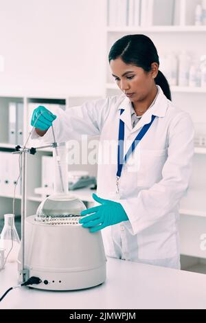 Eine attraktive junge Wissenschaftlerin, die mit einer Zentrifuge und einem konischen Kolben in einem Labor arbeitet. Stockfoto