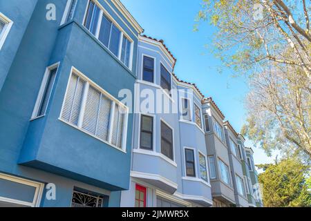 Fassade von Stadthäusern in einer Reihe mit verschiedenen Wandfarben in San Francisco, Kalifornien. Stadthäuser mit Bug- und Erkerfenstern in einem niedrigen Winkel Stockfoto