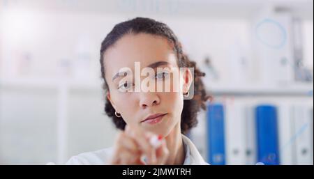 Einige revolutionäre neue Theorien. Ein junger Wissenschaftler schreibt Notizen an einer Glaswand in einem Labor. Stockfoto