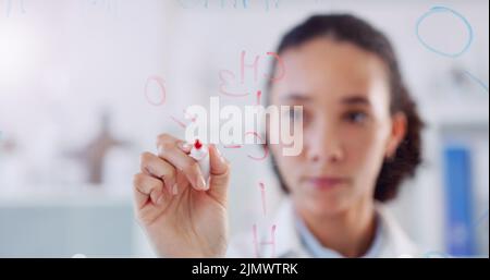 Jedes Detail summiert sich. Aufnahme eines jungen Wissenschaftlers, der in einem Labor molekulare Strukturen auf einer Glaswand zeichnete. Stockfoto