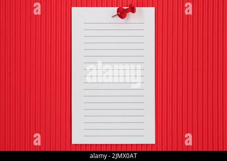 Weißes liniertes Papier, auf rotem Hintergrund fixiert Stockfoto