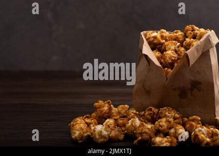 Karamellisiertes Popcorn in einer Papiertüte auf einem hölzernen Küchentisch Stockfoto