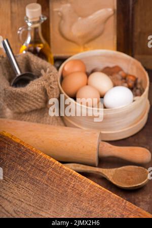 Holzlöffel, Spatel, Küchenutensilien auf einem Holztisch. Einfache Produkte - Mehl, Butter, Nüsse und Eier auf einem Holztisch Stockfoto