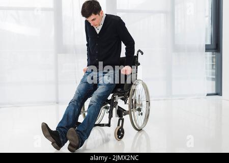 Junger Mann versucht, aus dem Rollstuhl zu kommen Stockfoto
