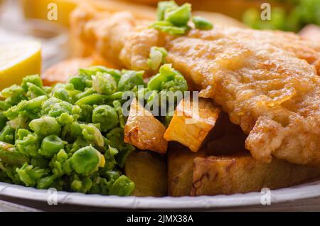 Traditionelle britische Street Food Fish und Chips mit Erbsenpüree auf Papier Platte Stockfoto