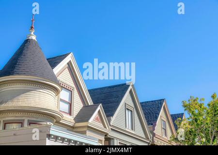 Reihe von Queen anne Häusern mit dekorativen Schindeln auf dem Gipfel von San Francisco, Kalifornien. Auf der linken Seite befindet sich ein Turm mit Dachschindeln und Stockfoto