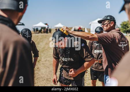 Horben, Deutschland. 17.. Juli 2022. Supervisor Jürgen Kenk (r) quetscht einen nassen Schwamm über den Hals von Simon Hug (l), Schleppermitglied des TC Feuerstein-Horben. Nach Angaben des Deutschen Turf-Sport- und Tauziehen-Verbandes (DRTV) gibt es bundesweit rund 600 bis 700 aktive Schlepper, die meisten davon im Süden. Tauziehen gilt als eine der ältesten Sportarten überhaupt: Wandgemälde, auf denen Mannschaften von Jungen an einem Seil ziehen, sind schon im alten Ägypten bekannt. (Um zu dpa ''Rope up!' - Das Tauziehen des Krieges ist mehr als nur ein Test der Stärke') Quelle: Philipp von Ditfurth/dpa/Alamy Live News Stockfoto