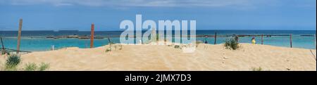 An einem sonnigen Tag laufen Menschen hinter Stacheldraht am Strand in der verlassenen Stadt der Geisterstadt Varosha Famagusta. Stockfoto