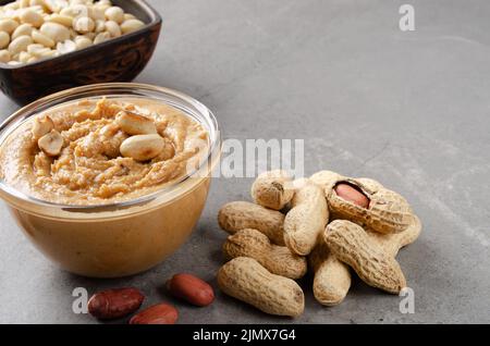 Niedrige Winkelansicht an der Glasschale mit Erdnussbutter auf Steintisch. Gesundes Esskonzept Stockfoto