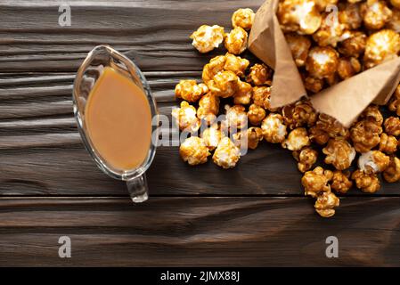 Karamellisiertes Popcorn in Papiertüte auf hölzernen Küchentisch flach legen Stockfoto